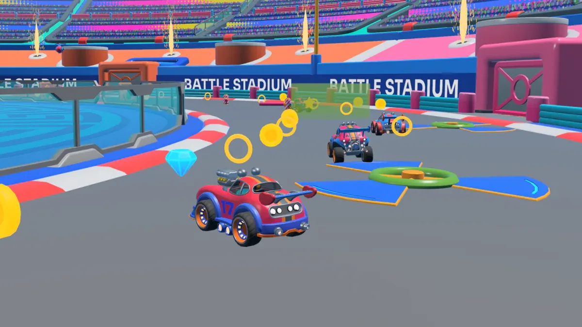 A red and blue toy car on a stadium straight, chasing two rivals along a chain of gold rings.